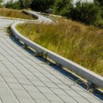 a wooden walkway with grass and trees