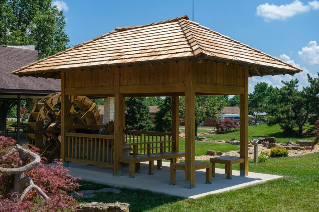 Wooden gazebo with seating in a sunny garden